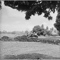 Ouvrier tahitien travaillant au terrassement avec un tractopelle civil, camp d'Arue (?), vers 1963-1964.