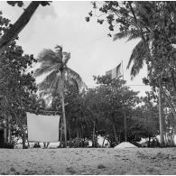 Infrastructures de la zone de vie. Peut-être sur l'atoll d'Hao. Place d'armes et écran de projection de cinéma en plein air.