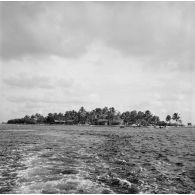 Vue depuis l'eau du rivage et du camp militaire. Peut-être la base Hortensia sur l'atoll de Moruroa.