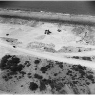 Vue aérienne de chantier de construction sur l'atoll, engins du génie, tas de minéraux pour la construction. Peut-être l'atoll de Moruroa.