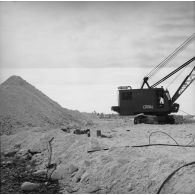 Chantier de construction de piste, engin de levage Epinal. Peut-être sur l'atoll de Moruroa.