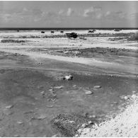 Engins rouleaux-compresseurs du génie et camion-benne sur un chantier de construction de piste. Peut-être sur l'atoll de Moruroa.