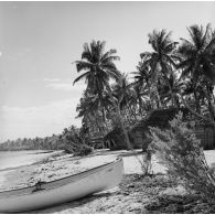 Hutte de la zone de vie sur le rivage avec barque. Peut-être sur l'atoll de Moruroa.