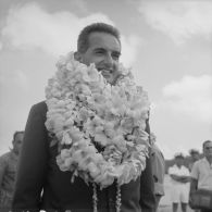 Portrait d'Alain Peyrefitte, ministre de l'Information, colliers de fleurs autour du cou, lors d'une cérémonie. A Vaitape (Bora-Bora).