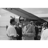 Le général Charles De Gaulle, président de la République, discute avec un photographe, en présence de Pierre Messmer, ministre des Armées, au pied de l'avion à l'aéroport de Moruroa. En arrière-plan, Pierre Billotte, ministre des Départements et territoires d'Outre-mer, et Alain Peyrefitte, ministre de la Recherche scientifique et des Questions atomiques et spatiales.