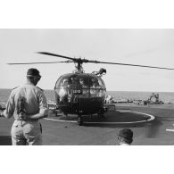 Départ du général De Gaulle du croiseur De Grasse après le déclenchement de l'essai nucléaire Bételgeuse, et du vice-amiral Jean Lorain, commandant du groupe opérationnel des expérimentations nucléaires (GOEN), par hélicoptère Alouette III.