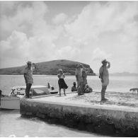 Tournée dans les îles Tuamotu-Gambier du contre-amiral Jacques Thabaud, commandant le Centre d'expérimentations du Pacifique (CEP), accompagné de son épouse qui filme la scène. Salut sur la jetée. A Mangareva (Gambier).