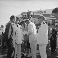 Aimé Grimald, gouverneur de la Polynésie française, accueille Jean Sainteny, ministre des anciens combattants et victimes de guerre, à l'aéroport, en présence du contre-amiral Jacques Thabaud, commandant le Centre d'expérimentations du Pacifique (CEP).