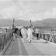 Aimé Grimald, gouverneur de la Polynésie française, et le contre-amiral Jacques Thabaud, commandant le Centre d'expérimentations du Pacifique (CEP), sur le pont de la Taunoa lors de son inauguration, Fare ute port de Papeete, 6 juin 1964, en présence de journalistes (photographe, presse radiophonique).