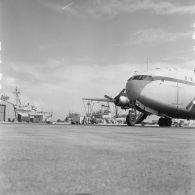 Avion Breguet Deux Ponts au parking de l'aérodrome de Moruroa. En arrière-plan, le port, le bâtiment de soutien santé (BSS) Rance (A618) et le bâtiment de soutien logistique (BSL) Tarn (A771) à quai.