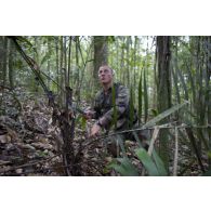 Un stagiaire coupe une feuille de palmier pour réaliser un abri feu sur un bivouac en zone d'instruction de Tuff, en Guyane française.