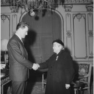 Femme rapatriée d'Algérie serrant la main d'un homme à l'occasion d'une remise de médaille départementale et communale.