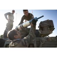 Des soldats du 1er régiment de chasseurs (RCh) chargent un obus de 120 mm à bord d'un char AMX-Leclerc à Cincu, en Roumanie.