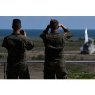 Des observateurs polonais observent un tir de roquette par un lance-roquettes unitaire (LRU) du 1er régiment d'artillerie (RA) à Cap Midia, en Roumanie.