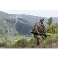 Un soldat américain du 32e régiment d'infanterie monte une mitrailleuse M240 sur un point haut pour une reconnaissance du secteur de Brădet, en Roumanie.