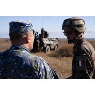 Un agent de la police militaire roumaine encadre une séance de tir au canon antiaérien de 20 mm sur véhicule de l'avant blindé (VAB) T-20/13 du 54e régiment d'artillerie (RA) à Cap Midia, en Roumanie.