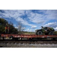 Des soldats guident le chargement d'un véhicule blindé léger (VBL) à bord d'un train en gare de Voila, en Roumanie.