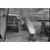 Maintenance sur la jeep Brouillard de la 2e division blindée (2e DB) par un mécanicien d'une unité du matériel.