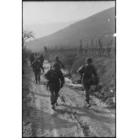 Patrouille de fantassins de la 3e division d'infanterie américaine (DIUS) sur un chemin boueux.