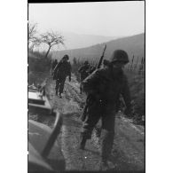 Patrouille de fantassins de la 3e division d'infanterie américaine (DIUS) sur un chemin boueux.