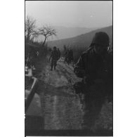 Patrouille de fantassins de la 3e division d'infanterie américaine (DIUS) sur un chemin boueux.