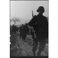 Patrouille de fantassins de la 3e division d'infanterie américaine (DIUS) sur un chemin boueux.