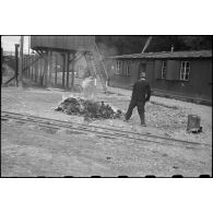 Des pompiers allemands brûlent les vêtements souillés des déportés qui passent à l'épouillage et à qui on fournit des vêtements propres dans le camp de Vaihingen récemment libéré.