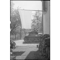 Un char M3 Stuart de la 1re division blindée (1re DB) traverse un village dans lequel les Allemands ont hissé des drapeaux blancs.