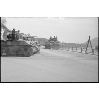 Un chasseur de chars M10 (ou TD M10) et un char léger M3 Stuart de la 1re division blindée (1re DB) progressent sur une route qui longe probablement le Rhin.