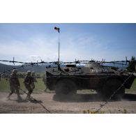 Des soldats roumains progressent en couverture d'un véhicule blindé ABC-79M sur le champ de tir à Lunca de Sus, en Roumanie.