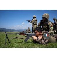 Un soldat du 35e régiment d'infanterie (RI) tire au fusil mitrailleur RPK encadré par un instructeur roumain sur le champ de tir à Lunca de Sus, en Roumanie.