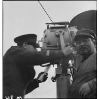 Un second maître utilise un projecteur à bord du chalutier de la marine marchande Roche noire, réquisitionné et armé par la Marine nationale comme dragueur de mines auxiliaire.