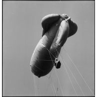 Ballon d'observation captif s'élevant dans les airs, avec ses câbles de retenue.