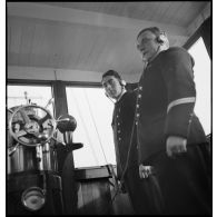 Portrait du lieutenant de vaisseau, commandant le patrouilleur La Lorientaise en compagnie d'un officier marinier, écouteurs sur les oreilles, à la passerelle de commandement.