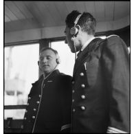 Portrait du lieutenant de vaisseau, commandant le patrouilleur La Lorientaise en compagnie d'un officier marinier, écouteurs sur les oreilles, à la passerelle de commandement.