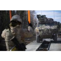 Un soldat britannique du Corps of Royal Engineers guide un véhicule blindé multi-rôles (VBMR) Griffon sur des travures pour le franchissement d'un cours d'eau à Tapa, en Estonie.