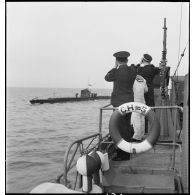 Un officier et un officier marinier, à bord du chasseur de sous-marins n°5, observent l'un d'entre eux naviguant sur leur bord.