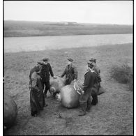 L'équipe de marins démineurs de la Marine nationale, dirigée par le second maître Dudouard, est réunie autour de mines sous-marines désarmorcées rassemblées près des plages.