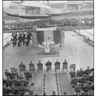 L'aumônier du cuirassé Dunkerque célèbre une messe sur le pont devant la catapulte à flêche télescopique des hydravions du bâtiment.