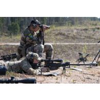 Un tireur d'élite américain de la 101e Airborne observe le terrain dans la lunette d'un fusil PGM Hécate II sous la supervision d'un spotter de la 13e demi-brigade de la légion étrangère (DBLE) à Tapa, en Estonie.