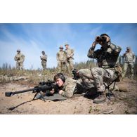 Un tireur d'élite américain de la 101e Airborne observe le terrain dans la lunette d'un fusil PGM Hécate II sous la supervision d'un spotter de la 13e demi-brigade de la légion étrangère (DBLE) à Tapa, en Estonie.