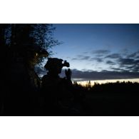 Un commando parachutiste (GCP) du 8e régiment parachutiste d'infanterie de marine (RPIMa) observe le terrain au moyen de ses jumelles de vision nocturne après avoir sauté sur Viitna, en Estonie.