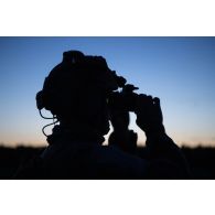 Un commando parachutiste (GCP) du 8e régiment parachutiste d'infanterie de marine (RPIMa) observe le terrain au moyen de ses jumelles de vision nocturne après avoir sauté sur Viitna, en Estonie.