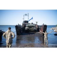 Des soldats britanniques des Royal Marines encadrent l'embarquement d'un char Challenger 2 des Queen's Royal Hussars à bord d'un chaland de transport de matériel landing craft utility (LCU) de la Royal Navy à Paldiski, en Estonie.