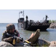 Un légionnaire de la section amphibie sécurise le débarquement d'un char Challenger 2 britannique des Queen's Royal Hussars depuis un chaland de transport de matériel landing craft utility (LCU) de la Royal Navy sur la plage de Paldiski, en Estonie.