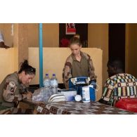 Les auxiliaires sanitaires Mathilde et Mélody examinent un patient pour une consultation au centre de santé d'Arlit, au Niger.