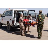 Le personnel de la 8e antenne chirurgicale aérotransportable (ACA) aide un soldat belge à débarquer un brancard depuis une ambulance à Niamey, au Niger.