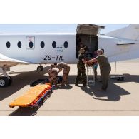 Le personnel de la 8e antenne chirurgicale aérotransportable (ACA) aide ses homologues belges et allemands pour l'évacuation d'un blessé depuis un avion Beechcraft 1900 Beechliner sud-africain à Niamey, au Niger.