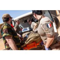 Le personnel de la 8e antenne chirurgicale aérotransportable (ACA) aide un soldat belge à évacuer un blessé par ambulance à Niamey, au Niger.