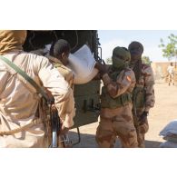 Des gardes nationaux nigériens déchargent du mil depuis un camion GBC-180 à Dougou Saro, au Niger.